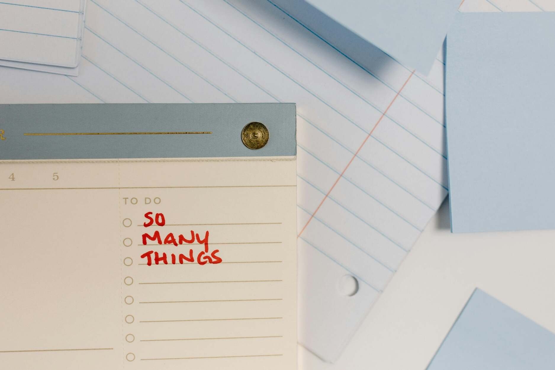 A to-do list reads SO MANY THINGS in red ink, surrounded by lined and blue notepaper, perfect for tracking Squarespace help tasks.