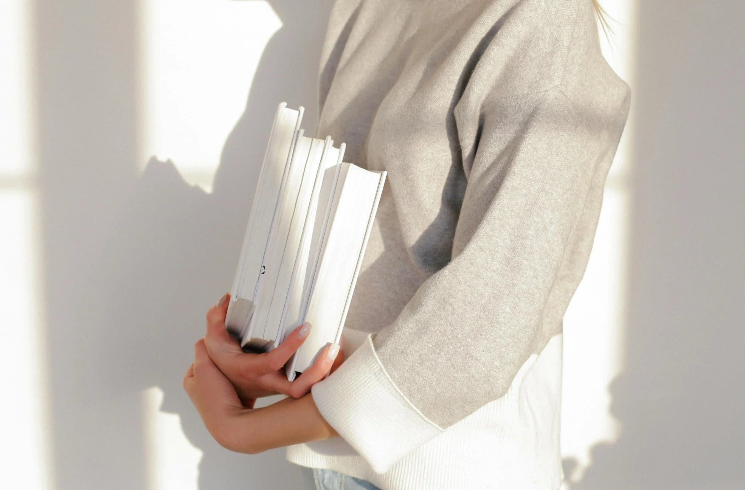 Squarespace website designer in a light sweater holding several books, reflecting the combination of strategy, creativity, technical expertise, and professionalism.